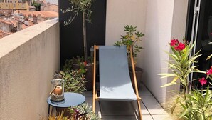 A small balcony with a blue chair, a table, and potted plants. - Appartement en Étage Élévé Avec Terrasses (Marseille)