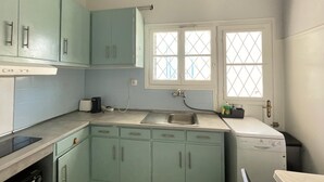Une cuisine compacte avec des meubles de couleur turquoise, un four encastré et un lave-vaisselle.