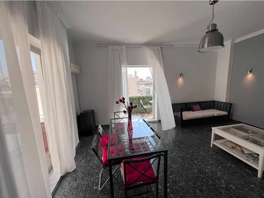 Ein modernes Wohnzimmer mit einem Glastisch, roten Sitzgelegenheiten, einem schwarzen Sofa und einem weißen Couchtisch.