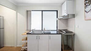 Une cuisine compacte dotée d’une fenêtre, d’une hotte en acier inoxydable et d’un four encastré.