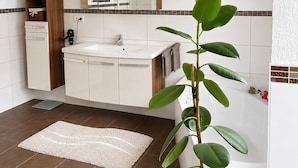 A bathroom with a sink, mirror, cabinets, and a plant.