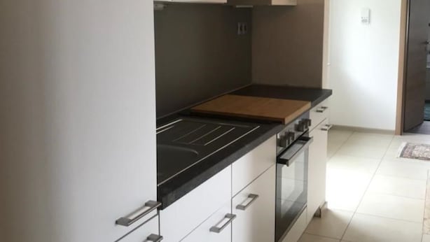 A modern kitchen with white cabinets, a black countertop, and a built-in oven.