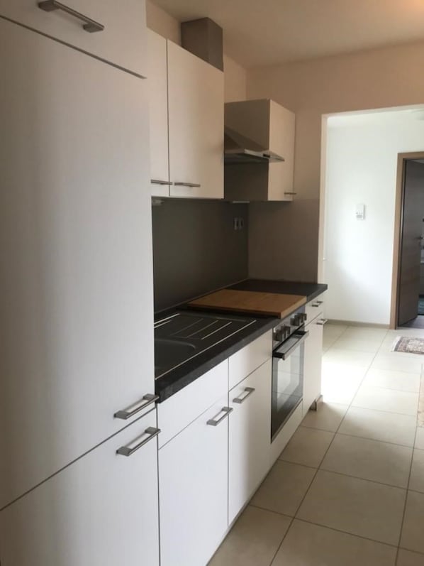 Una cocina moderna con armarios blancos, encimera negra y horno integrado.