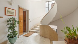 A modern interior with a marble staircase, a wooden door, a framed picture, and potted plants. - Bright and Spacious 5BR Apartment in Pariol (Roma)