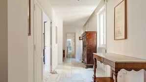 A hallway with a marble floor, wooden furniture, and framed artwork on the walls. - Bright and Spacious 5BR Apartment in Pariol (Roma)