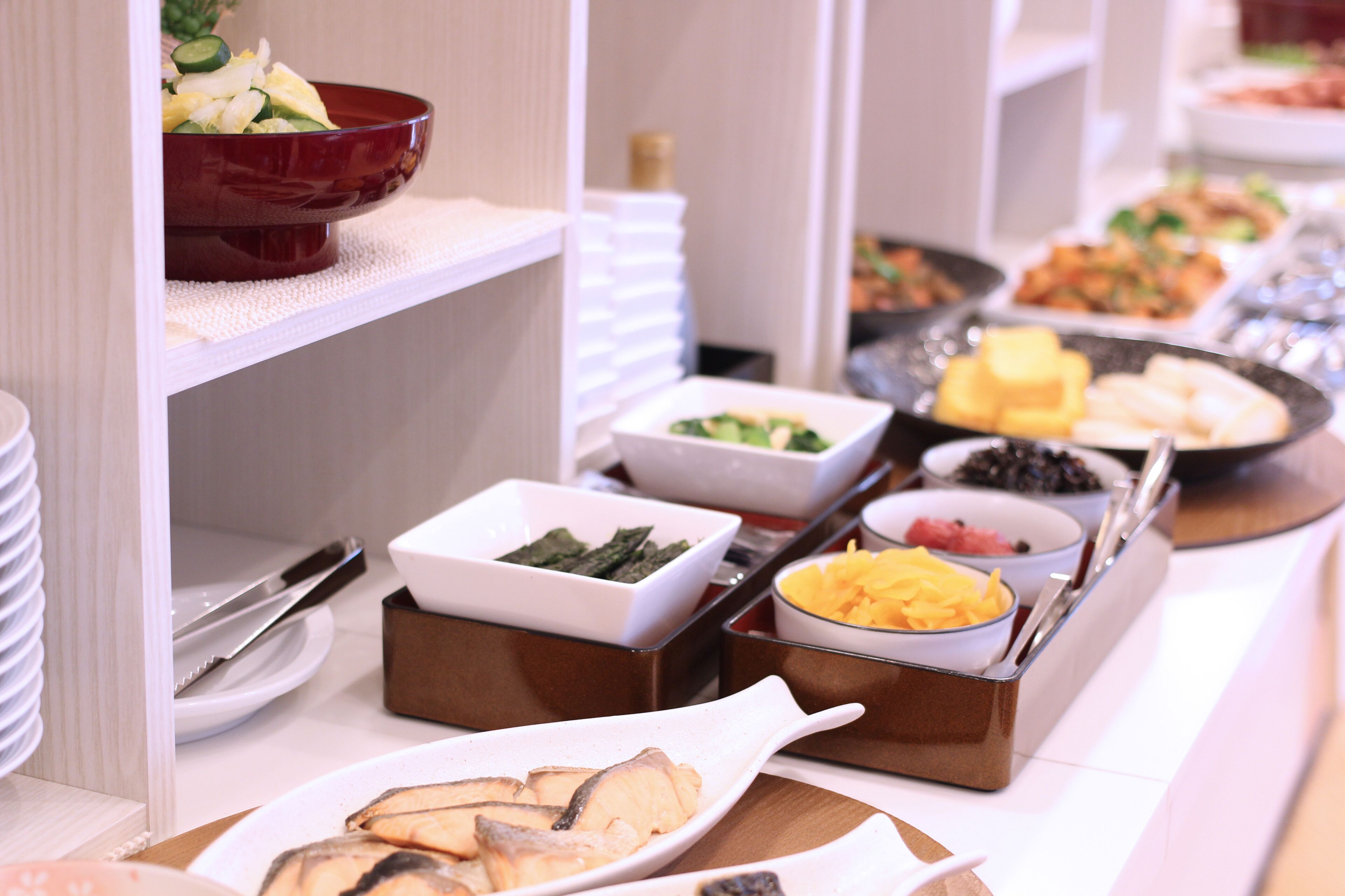 A buffet with various dishes including fish, vegetables, and fruits.