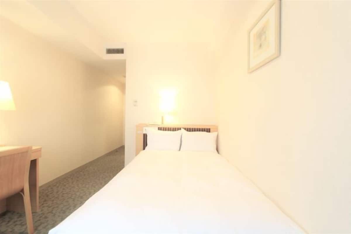 A hotel room with a bed, a desk, and a nightstand.