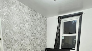 Ein Schlafzimmer mit einem Bett, einem Nachttisch, einem Fenster und einer raumschönlichen Tapete.