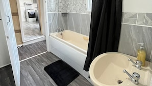 Ein modernes Badezimmer mit Badewanne, Waschbecken und Duschvorhang.