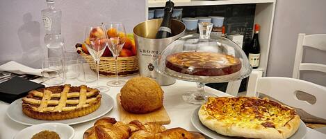 A table set with various food items including a pie, croissants, cheese, and ham.