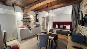A cozy hotel room with a kitchen area, a dining table, and a comfortable bed. - Nobilia Dimore - Suite & Spa (Pratovecchio Stia)