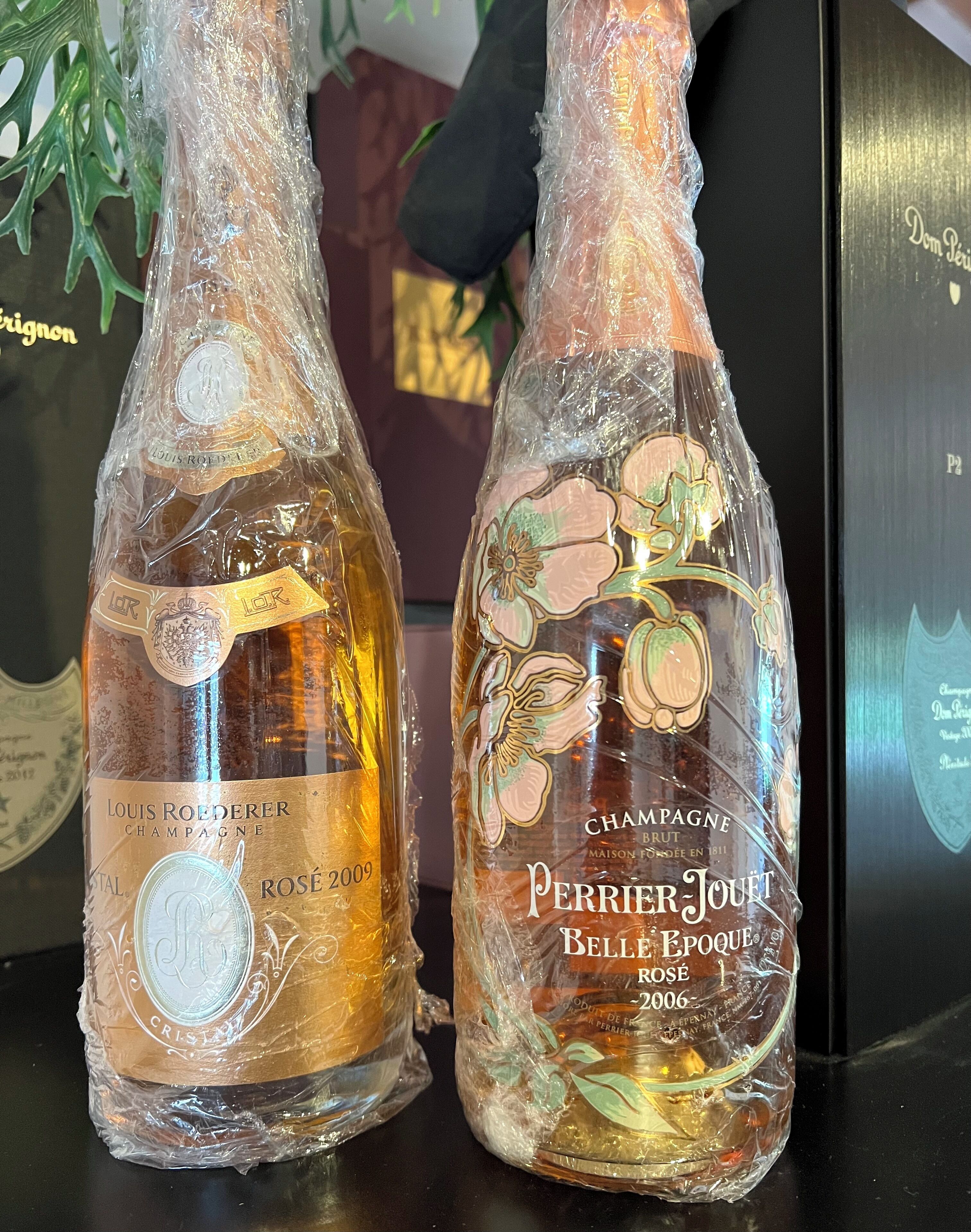 Two bottles of champagne, Louis Roederer and Perrier Jouet, wrapped in plastic.