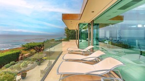 Un balcon moderne avec des garde-corps en verre donnant sur l’océan.