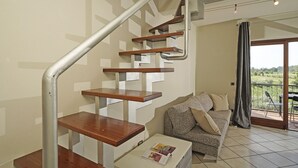 Un interior moderno con una escalera de madera, un sofá y un balcón con vistas.