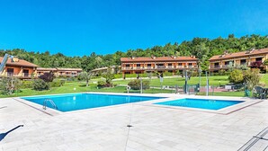 Un hotel con dos piscinas, un césped bien cuidado y un cielo azul despejado.
