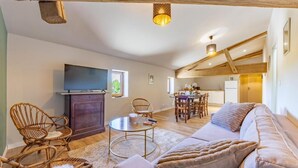 Una sala de estar acogedora con sofá, sillones, televisor y comedor.