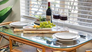 A dining table with a bottle of wine, two glasses of red wine, a plate of cheese, and a bowl of grapes. - Little Havana Retreat, Steps from the Beach - King Size Bed & Gulf Bliss! (Indian Rocks Beach)