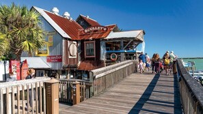 A wooden pier with a restaurant named 'SCULLERY'S' and a sign for 'my sandbox family fun.'