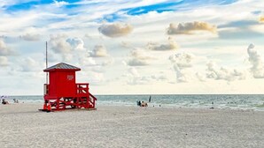 Une tour de surveillance des sauveteurs sur une plage, avec un ciel dégagé et quelques nuages.