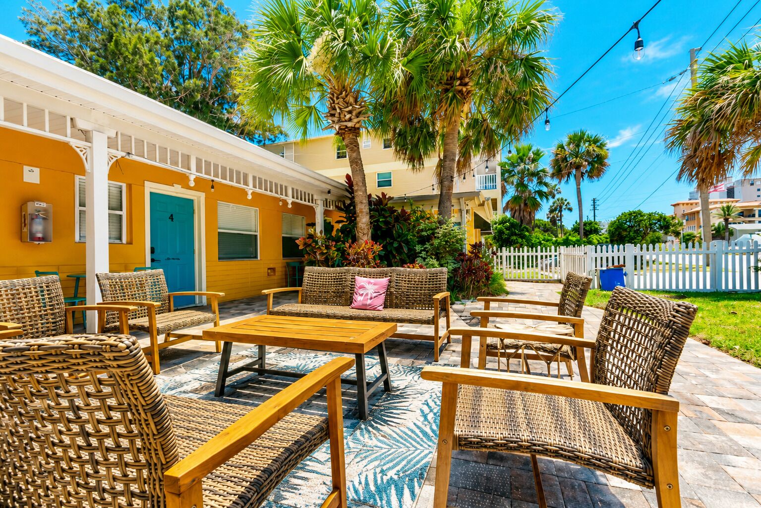 A patio area with wicker furniture, a wooden table, and a blue door.