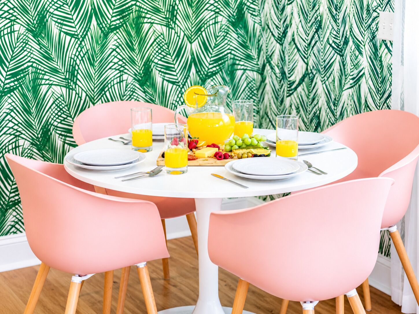A dining table set with plates, cutlery, glasses, and a fruit platter.
