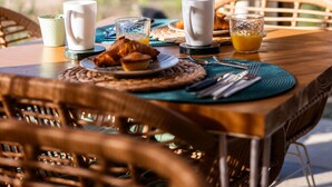 A dining table with a wicker chair, a white mug, a glass of orange juice, and a croissant. - Tenuta Dorolivo Guest House e B&B (Giurdignano)