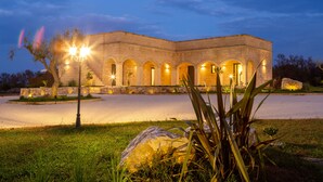 A stone building with arched walkways and a well-lit entrance. - Tenuta Dorolivo Guest House e B&B (Giurdignano)
