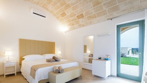 A modern bedroom with a large bed, bedside tables, a bench, a dresser, and a large window with a view. - Tenuta Dorolivo Guest House e B&B (Giurdignano)