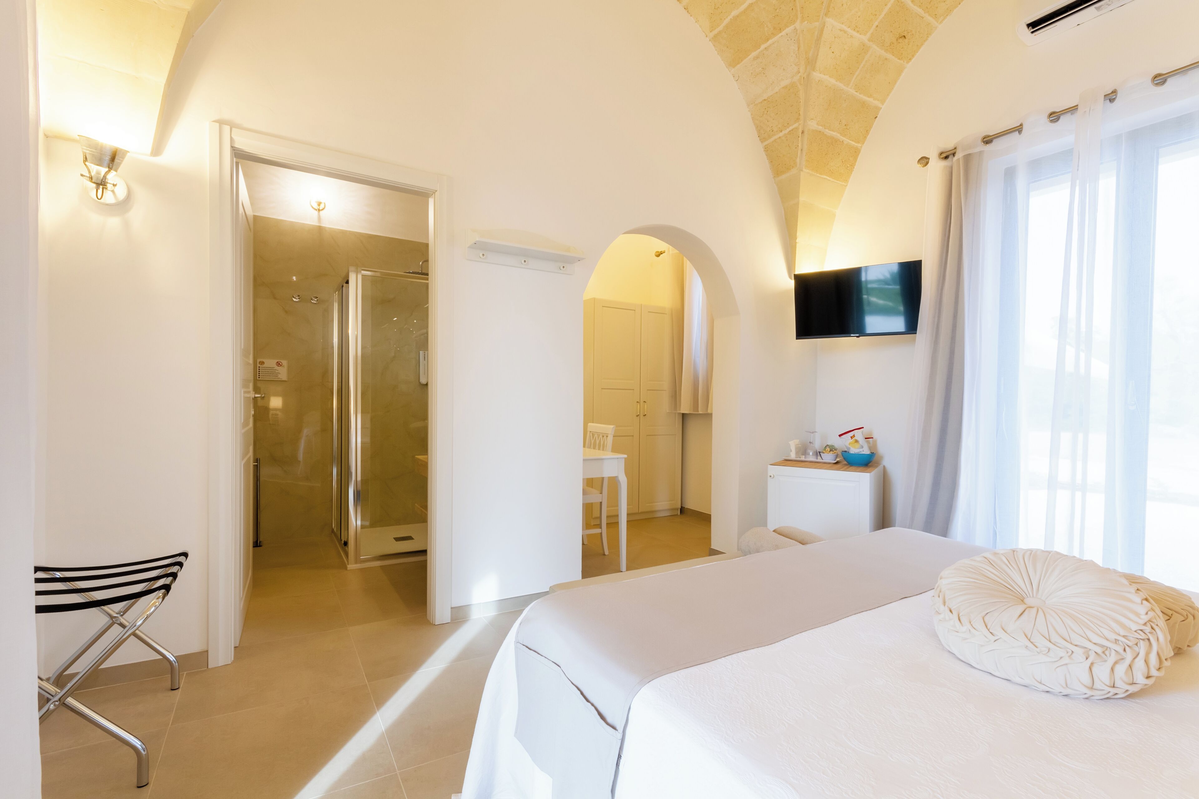 A hotel room with a bed, a TV, a shower, and a desk.