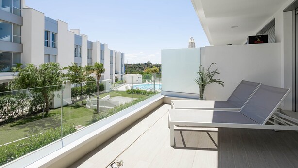 A modern balcony with a pool view, white walls, and a glass railing. - RDR317 - Stylish 3 bedroom Le Mirage close to beach (Estepona)