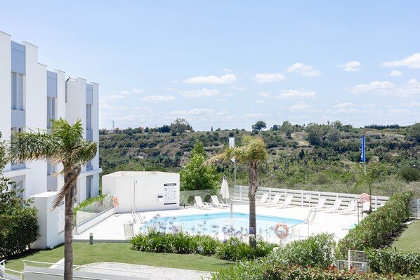 Un hotel moderno con piscina rodeada de vegetación y vistas a un paisaje montañoso.