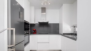 A modern kitchen with stainless steel appliances, white cabinetry, and a black countertop. - RDR317 - Stylish 3 bedroom Le Mirage close to beach (Estepona)