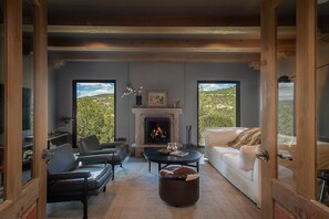 A living room with a fireplace, a sofa, a coffee table, and a view of the outdoors.