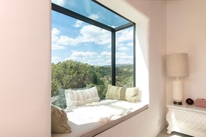 A room with a large window, a white lamp, and a view of greenery. - Takoda (Santa Fe)