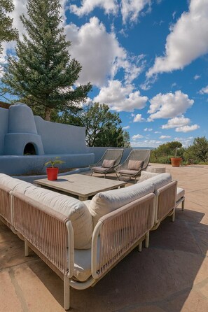 A sunlit outdoor seating area with a sofa and chairs, a small table, and a potted plant.