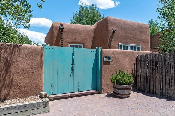 A building with a stucco exterior, a turquoise gate, and a wooden fence.