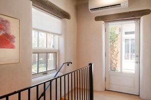 A staircase with a handrail, a door with a glass panel, and a window with blinds.