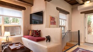 A cozy living room with a sofa, a TV, a small pig figurine, and a wooden floor.