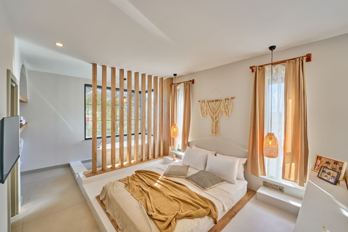 Een moderne slaapkamer met een bed, houten latten, een nachtkastje, een lamp en een raam met gordijnen.