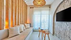 Una sala moderna con un sofá, una mesa de comedor con un centro de mesa y un televisor de pantalla plana grande montado en una pared con textura.