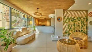 Un moderno vestíbulo de hotel con mostrador de recepción, zona de estar y decoración de bambú.