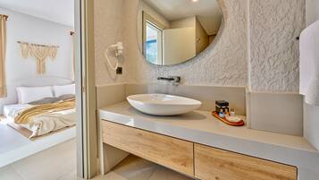 Een moderne badkamer met een ronde spiegel, een witte wastafel en een houten opbergmeubel.