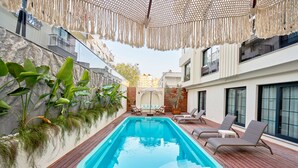 Una piscina con sillas de descanso, una terraza de madera y vistas a la ciudad.
