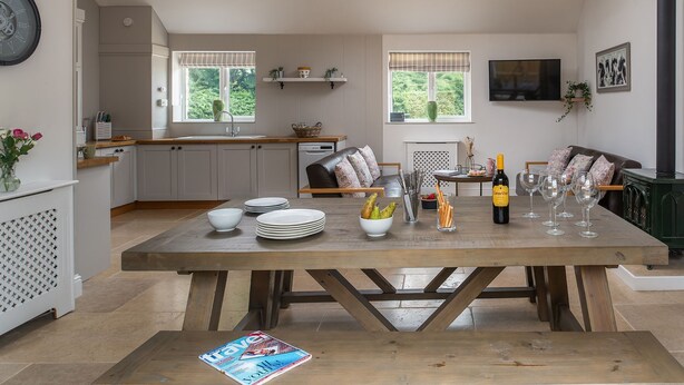 Un'ampia cucina con zona pranzo, tavolo in legno e una bottiglia di vino.