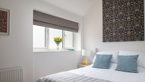 Una camera da letto con un letto, una finestra con vista, un comodino con lampada e una parete decorata con un'opera d'arte a motivi.