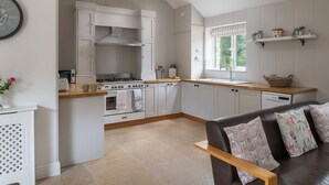 Una cucina moderna con mobili bianchi, forno integrato e finestra sopra il lavello.