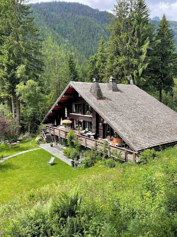 A lodge with a sloped roof, wooden deck, and a view of a forested mountain. - Large chalet, peaceful setting ideal for Cham adventures, Flégère & Grand Montet (Chamonix-Mont-Blanc)