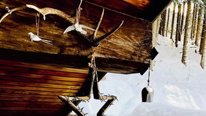 A rustic wooden cabin with a snow-covered exterior, a wooden ceiling with hanging decorations, and a hot tub in the foreground. - Large chalet, peaceful setting ideal for Cham adventures, Flégère & Grand Montet (Chamonix-Mont-Blanc)