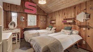 A cozy cabin-style bedroom with two beds, wooden walls, a large 'S' letter decoration, a mirror, and a window with a view of trees. - Large chalet, peaceful setting ideal for Cham adventures, Flégère & Grand Montet (Chamonix-Mont-Blanc)