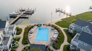 Ein Schwimmbecken, umgeben von Liegestühlen und einer Anlegestelle mit Booten.